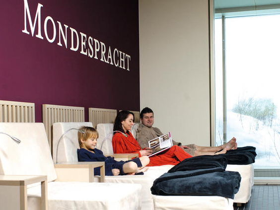 Een gezin relaxt samen op een comfortabele bank in de 'Mondesperacht' lounge van Ferienresort Bad Bentheim.