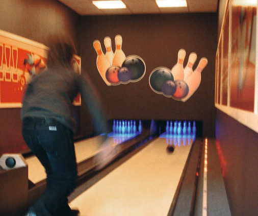 Een kind gooit een bowlingbal op de bowlingbaan van Ferienresort Bad Bentheim.