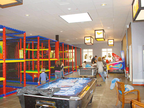 De kleurrijke indoorspeeltuin van Ferienresort Bad Bentheim met klimrekken en een airhockey tafel.