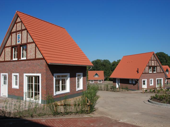 De buitenkant van de karakteristieke vakwerkhuizen van Ferienresort Bad Bentheim onder een strakblauwe hemel.