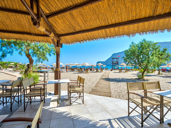 Het terras van de strandbar bij Fodele Beach Resort, met uitzicht op het zandstrand en de zee.