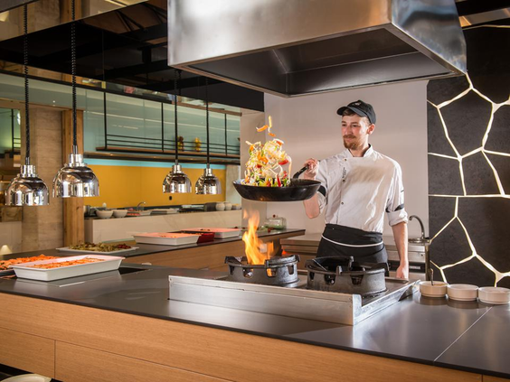 Een kok bereidt een gerecht met show cooking en grote vlammen in het restaurant van Fodele Beach Resort.