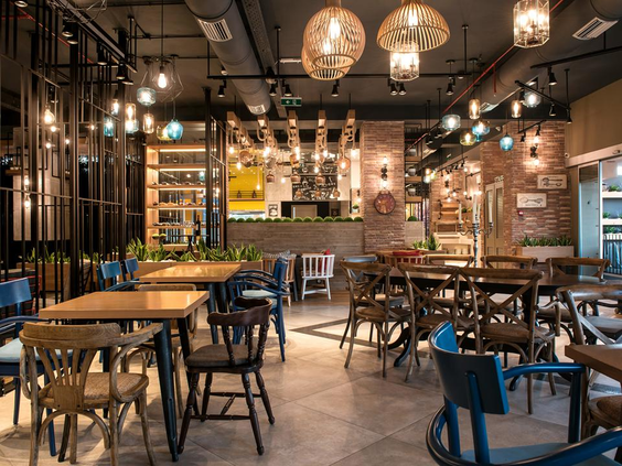 Het hippe, industrieel ingerichte interieur van een van de bars bij Fodele Beach Resort op Kreta, met houten tafels en sfeerverlichting.