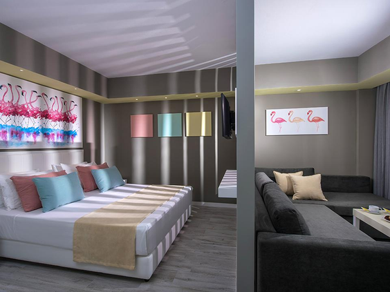 Een stijlvol ingerichte familiekamer bij Fodele Beach Resort, met vrolijke kleuren, meerdere bedden en een comfortabele zithoek.