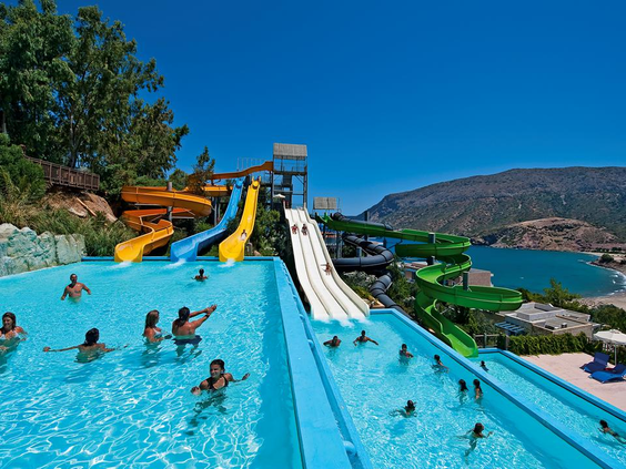 Kinderen en volwassenen genieten van de waterpret in het zwembad aan het einde van de multilane waterglijbaan bij Fodele Beach Resort.
