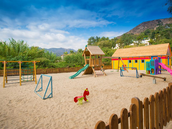 De leuke speeltuin in het zand bij Fodele Beach Resort op Kreta, met een kleurrijk speelhuisje, glijbaan en voetbaldoeltjes.
