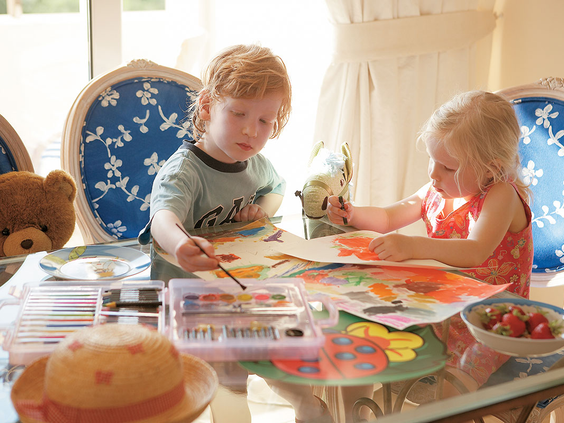 Twee jonge kinderen zijn creatief bezig met tekenen en verven in de gezellige Grecoland Kids' Club van Grecotel Club Marine Palace.