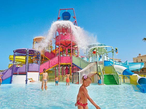 Het kleurrijke aquapark van Grecotel Club Marine Palace met een grote roze tuimel-emmer die water stort over de spelende kinderen.