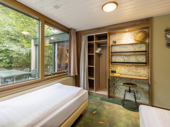 De kinderslaapkamer van een Avontuur cottage in Het Heijderbos, ingericht in ontdekkingsreizigerstijl met een landkaart en twee opgemaakte bedden.