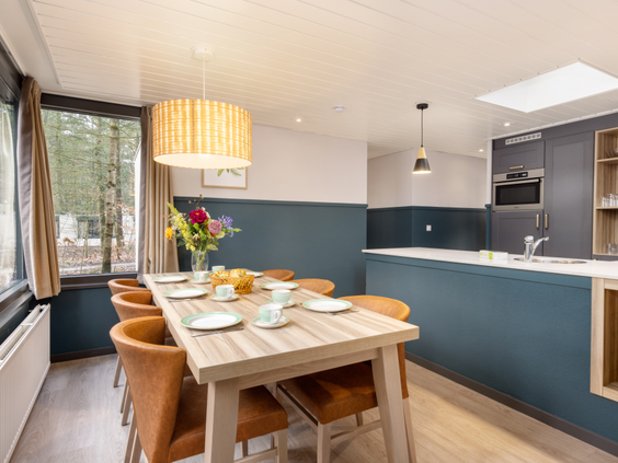 e modern ingerichte eethoek en keuken in een vernieuwde VIP cottage van Het Heijderbos, met een gedekte tafel die klaarstaat voor het ontbijt of diner.