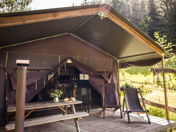 De buitenkant van een luxe glamping tent bij Hilserhof met een veranda, perfect voor comfortabel kamperen met het gezin.