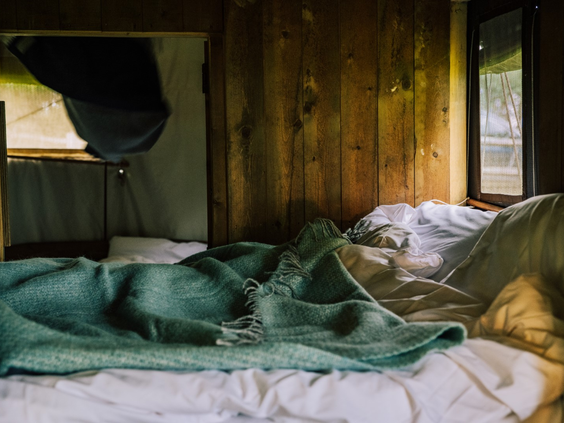 Comfortabel bed met zachte dekens en houten wanden in de glamping accommodatie van Hilserhof, voor een heerlijke nachtrust.