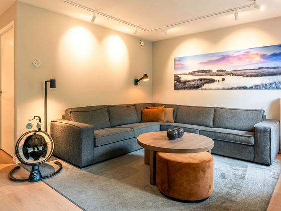 De sfeervol ingerichte woonkamer van de Newborn boerderij op Hof van Saksen, met een comfortabele hoekbank en een wipstoeltje voor de baby.