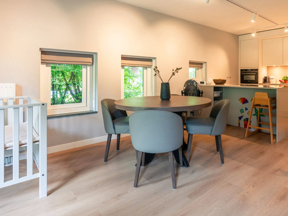 De ruime eethoek in de Newborn boerderij van Hof van Saksen, compleet met kinderstoel en open keuken, ideaal voor een gezinsontbijt.
