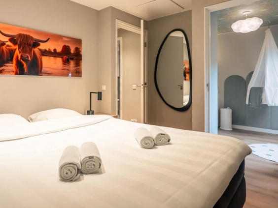 De comfortabele ouderslaapkamer met een opgemaakt tweepersoonsbed in de speciale Newborn boerderij op resort Hof van Saksen in Drenthe.