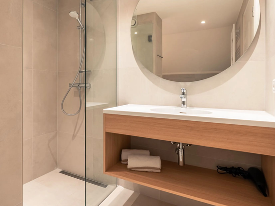 De moderne en luxe badkamer van de Newborn boerderij, uitgerust met een ruime inloopdouche, wastafel en spiegel.