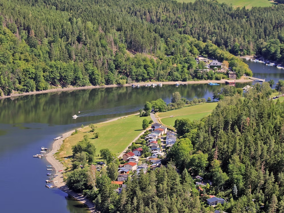 Luchtfoto van Hohenwarter Seehof in Nedersaksen, met het vakantiepark aan het meer, omringd door groene bossen, ideaal voor gezinsvakanties.