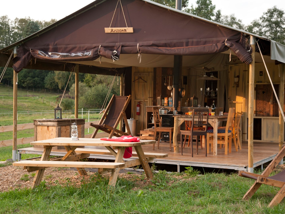 Een ruime en luxe glamping tent van Hohenwarter Seehof met een picknicktafel buiten, ideaal voor een avontuurlijke gezinsvakantie in de natuur.