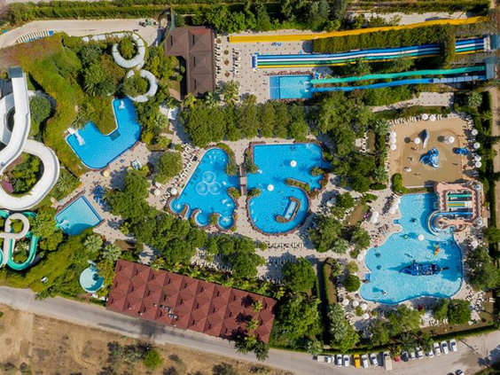 Luchtfoto van het enorme aquapark van Hotel Ali Bey Club in Side, Turkije, met talloze zwembaden en spectaculaire waterglijbanen.