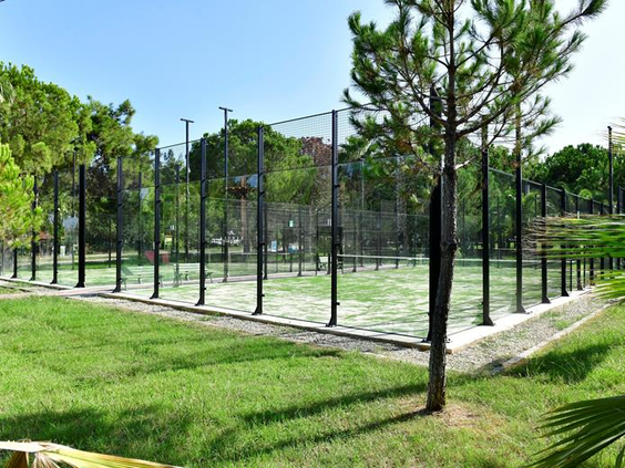 De professionele tennisbanen van Hotel Ali Bey Club in Side, omgeven door groene bomen en perfect onderhouden gras.