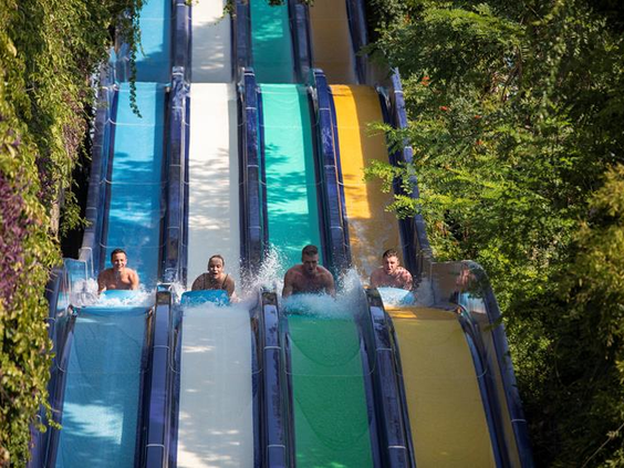 Kinderen en volwassenen racen tegen elkaar op de brede multislide waterglijbaan in het aquapark van Ali Bey Club in Side.