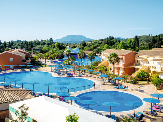 Overzicht van het grote zwembad bij de hotelkamers van Hotel Aqualand Resort op Corfu, omringd door ligbedjes en parasols.