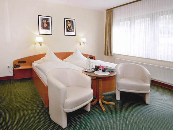 Comfortabele en lichte tweepersoonskamer in Hotel Burgfrieden met zachte bedden, zithoek en een groot raam, ideaal voor een gezinsvakantie in de Moezel.