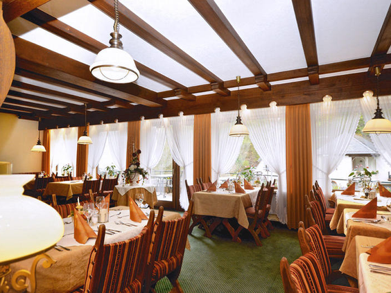 Gezellig en traditioneel ingericht restaurant van Hotel Burgfrieden met houten balkenplafond, mooi gedekte tafels en warme sfeerverlichting.