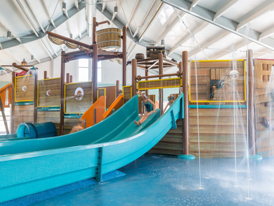 De overdekte waterspeeltuin in de vorm van een schip met een glijbaan in het zwembad van Strandpark De Zeeuwse Kust.