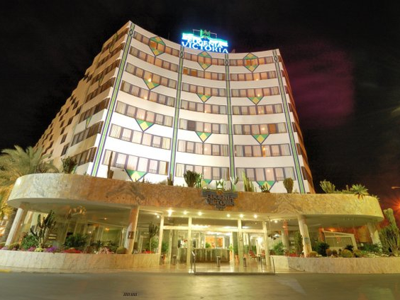 De verlichte voorkant van Hotel Eugenia Victoria in de avond in Playa del Inglés.