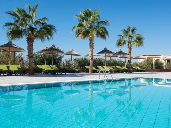 Rustig zwembad omringd door palmbomen en comfortabele ligbedjes met parasols, ideaal voor ontspanning in de Griekse zon.