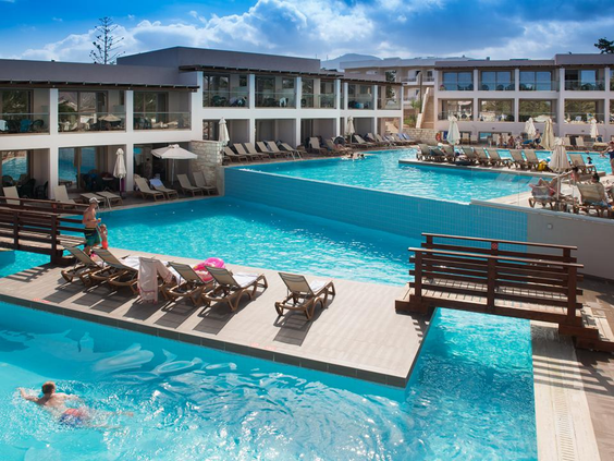 Luxe zwembad met een infinity-rand en speciale ligbedjes die in het ondiepe water staan, bij Hotel Gouves Waterpark Holiday Resort.