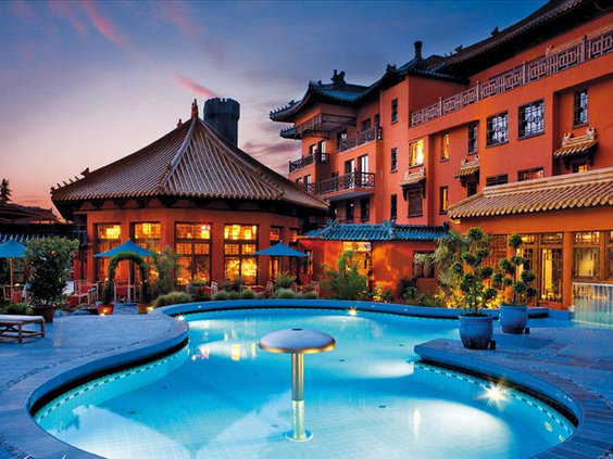 Het verlichte buitenzwembad van Hotel Ling Bao in Phantasialand bij schemering, met de sfeervolle Aziatische architectuur op de achtergrond.