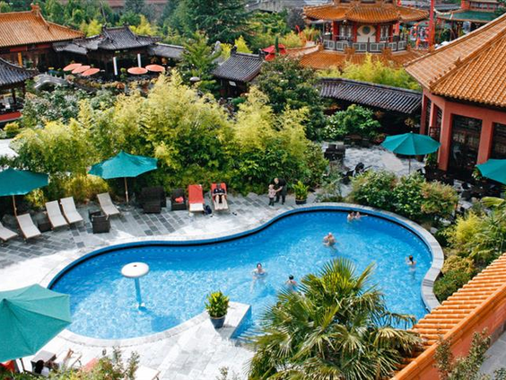 Luchtfoto van het organisch gevormde buitenzwembad van Hotel Ling Bao, omgeven door ligbedden en Aziatische tuinen.