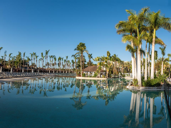 Het enorme, rustige zwembad van Maspalomas Princess, waarin de strakblauwe lucht en de vele palmbomen prachtig weerspiegelen.