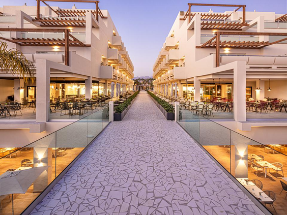 De sfeervol verlichte 'boulevard' tussen de hotelgebouwen van Maspalomas Princess in de avond, met uitzicht op de balkons.