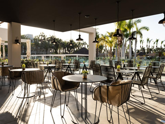 Het moderne en schaduwrijke restaurantterras van Maspalomas Princess op Gran Canaria, met hippe stoelen en uitzicht op het zwembad.
