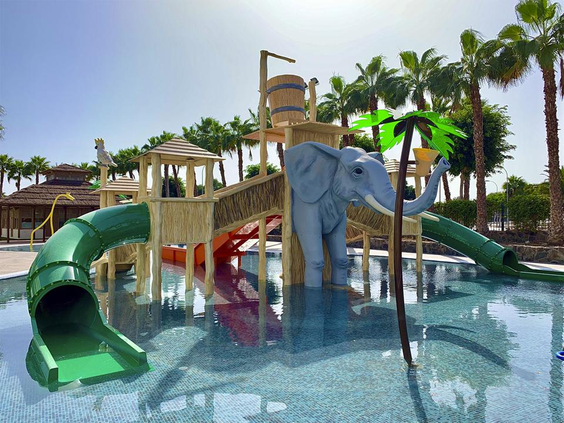 Het spetterende kinderbad van Maspalomas Princess met een groene tunnelglijbaan en een grote, grijze olifant die water spuit.