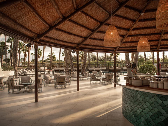 Het sfeervolle, overdekte buitenterras van Hotel Maspalomas Princess, met een rieten dak en relaxte zitjes.