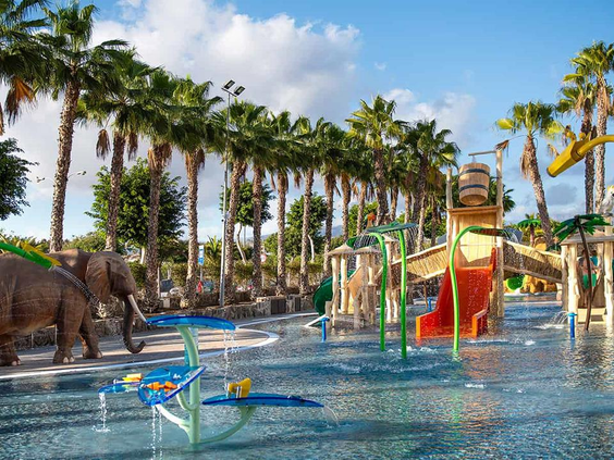 Het grote waterspuitpark van Maspalomas Princess, met olifantenbeelden, diverse watersproeiers en glijbanen, omringd door palmbomen.