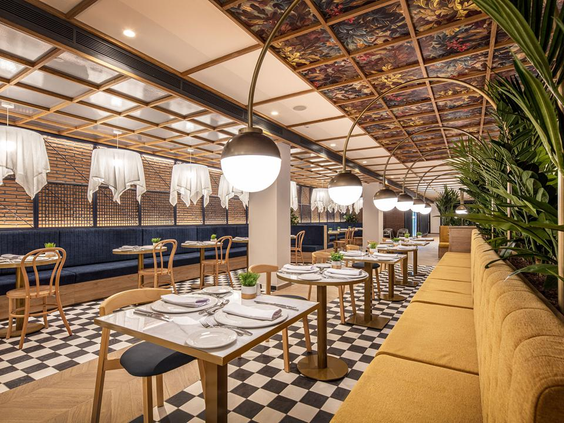 Het stijlvolle interieur van een restaurant in Hotel Maspalomas Princess, met een zwart-wit geblokte tegelvloer en comfortabele zitjes.