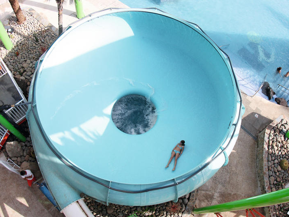 Een gast glijdt rond in de grote trechterglijbaan, de 'space bowl', in het waterpark van Paradise Lago Taurito.