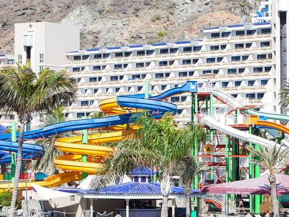 Een wirwar van gele, blauwe en groene waterglijbanen die door elkaar kronkelen bij het Paradise Lago Taurito waterpark op Gran Canaria.