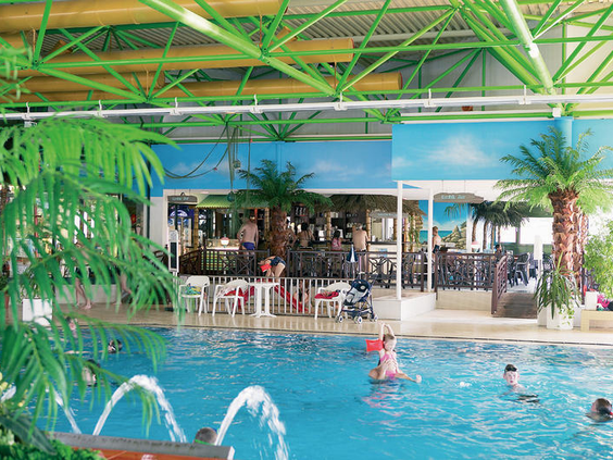 Het subtropische binnenzwembad Lagunen-Erlebnisbad, verbonden met Hotel Sauerland Stern, met palmbomen en badgasten in het water.