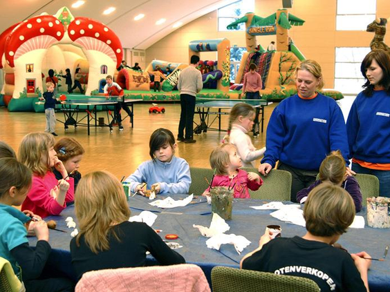 Kinderen zijn gezellig aan het knutselen aan tafel onder begeleiding van het animatieteam in de kidsclub van Hotel Sauerland Stern.
