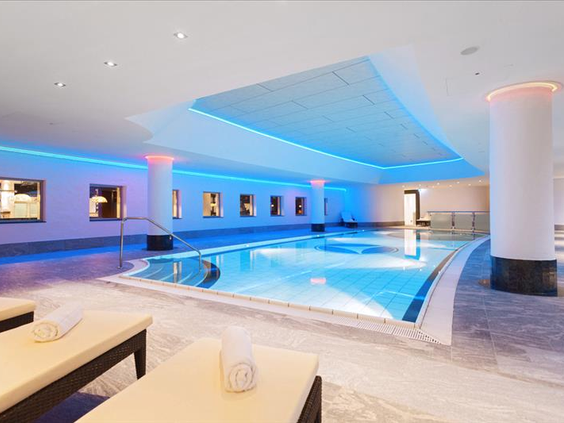 Het luxe en sfeervol verlichte binnenzwembad van Hotel Sauerland Stern met comfortabele ligbedden, speciaal voor hotelgasten.