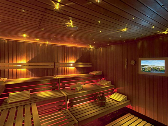 De ruime, houten Finse sauna in de wellness-afdeling van Hotel Sauerland Stern, met sfeervolle gekleurde verlichting onder de banken.
