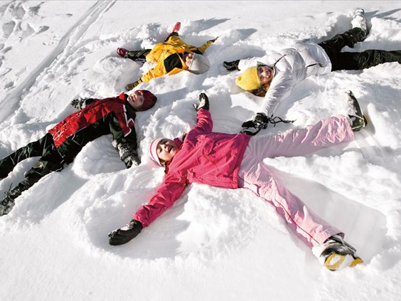 Een vrolijk gezin maakt sneeuwengelen in de diepe, witte sneeuw tijdens hun wintervakantie in Willingen, Sauerland.