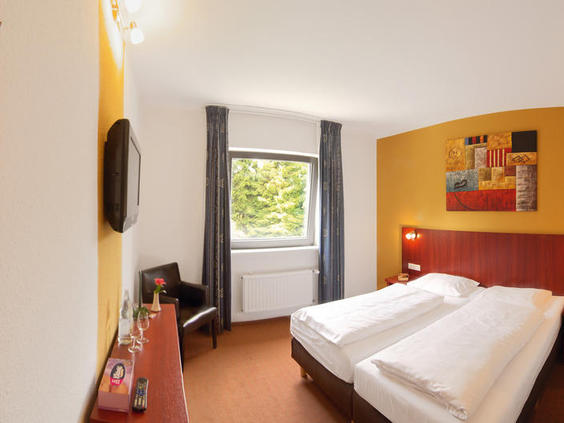 Een comfortabele en moderne familiekamer in Hotel Winterberg Resort, met opgemaakte bedden en een gezellige sfeer.