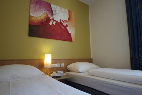 De netjes opgemaakte, comfortabele bedden in een hotelkamer van Hotel Winterberg Resort, klaar voor een goede nachtrust.